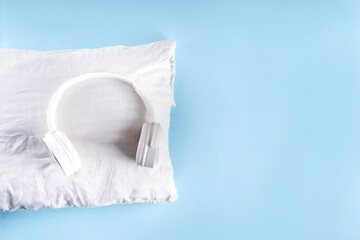 Sonic Hues and Noise for sleep concept with comfortable headphones and white pillow on light blue...
