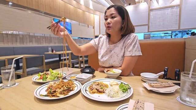 A customer is eating noodles, meat, and some vegetables at a restaurant in Bangkok, Thailand.