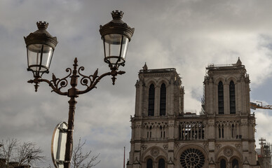 Fototapeta na wymiar Famous Notre Dame cathedral with Parisian streetlamps in the foreground. UNESCO World Heritage Site, Space for text, selective focus.