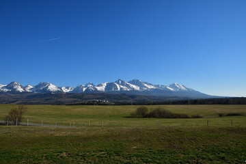 Green meadows, trees and forests and snow-capped peaks of the High Tatras