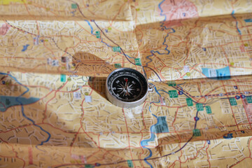 A compass lies on a paper map. Travel planning, direction of movement