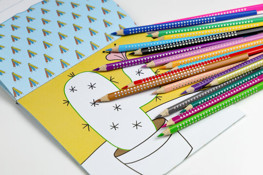 Colored pencils for drawing various colors and coloring book for children.