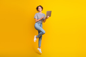 Full length photo of excited gorgeous person jump use netbook empty space isolated on yellow color background