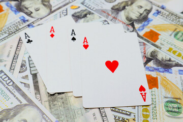 Four kind of ace cards over several one hundred dollar bills