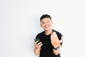 an Asian man shows an inviting gesture while holding his smartphone
