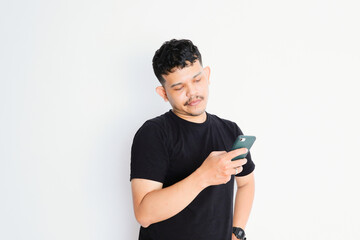 Portrait of unhappy Asian man in black shirt holding mobile phone with sad expression on face