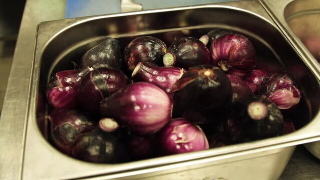 Following Cloes Up Shot of Washed, Peeled Red Onions in a Metal Bowl in a Restaurant Prepared for Cutting