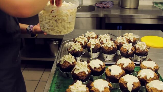 Following Cloes Up Shot of Confectioner Decorating Cupcakes with Popcorn and Chocolate Decorations