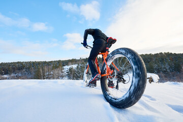 Fisheye action shot of professional cyclist riding bike over snow-covered mountain