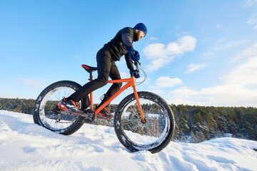 Concentrated man cycling alone over winter mountains by overcoming difficulties