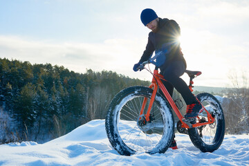 Serious hipster cyclist preparing for extreme rice in winter forest