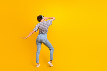 Fototapeta na wymiar Full body rear behind photo of overjoyed nice lady hand touch headphones dancing empty space isolated on yellow color background