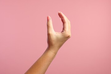 Woman holding something in fingers on pink background, closeup