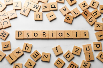 Word Psoriasis made of wooden squares with letters on white table, flat lay