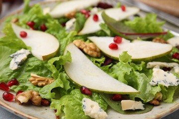 Delicious pear salad with pomegranate, walnuts and blue cheese on plate, closeup