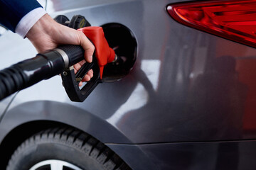Close up of male hand refueling gas tank of black luxury car at gas station, copy space - obrazy, fototapety, plakaty
