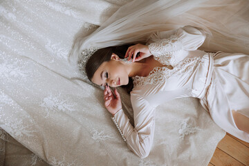 A beautiful young bride girl is lying in a beautiful robe. Morning of the bride before the wedding...