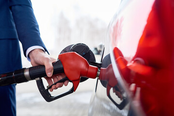 Side view closeup of strong male hand refueling gas tank of luxury car in modern petrol station
