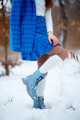 Stylish winter clothes for a walk. Warmth and color. Female legs. Spring is coming soon