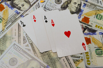 Four kind of ace cards over several one hundred dollar bills