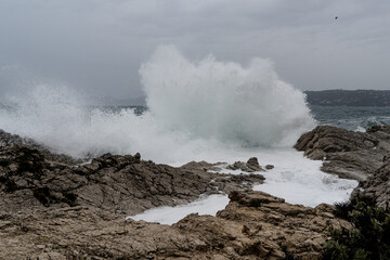 Fototapeta na wymiar Waves crashing during storm on a rocky shore. High quality photo. Climate natural event weather