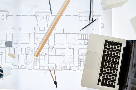 Top view background image of architects workplace with blueprints on table and laptop, copy space