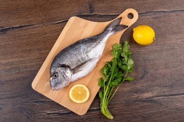Top view of delicious raw dorado fish on a cutting board and lemon with cilantro.