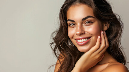 Naklejka premium Smiling woman with a hand gently touching her face, displaying clear skin and a joyful expression.