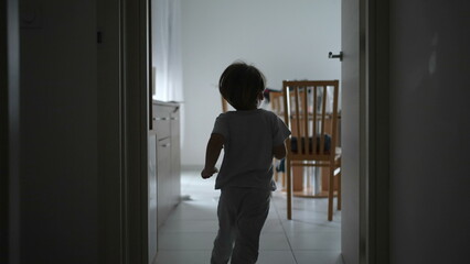 Back of child running at apartment corridor in slow-motion. One young boy having fun at home, dreamy silhouette of kid sprinting