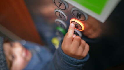 Child's hand pressing the sixth floor button inside elevator. Little boy going up at lift, ascending
