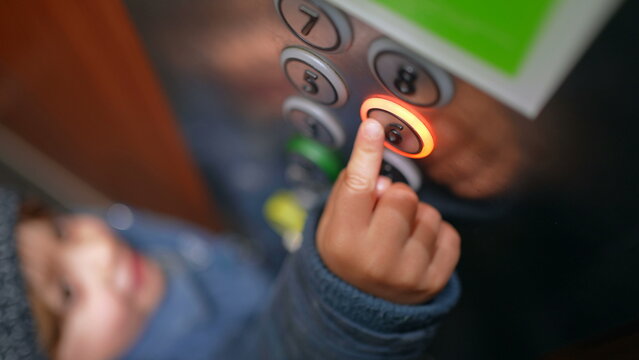 Child's hand pressing the sixth floor button inside elevator. Little boy going up at lift, ascending