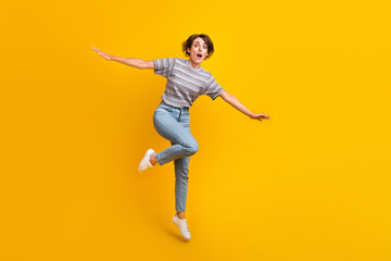 Full body photo of impressed crazy lady jump arms wings fly empty space isolated on yellow color...