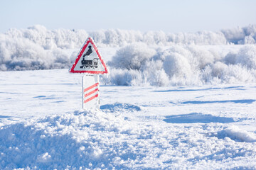 Railway crossing sign, snowdrifts and snow-covered trees in frost on the background