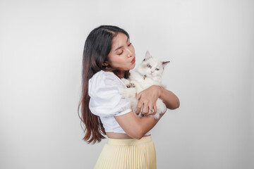 Portrait of young Asian woman holding cute ragdoll cat with blue eyes. Female hugging her cute long hair kitty isolated by white background. Adorable domestic pet concept. © Reezky