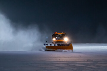 Snowblower truck cleans night airport apron in a snowstorm