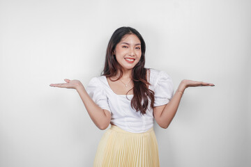 A cheerful Asian woman is pointing copy space beside her, isolated by white background.