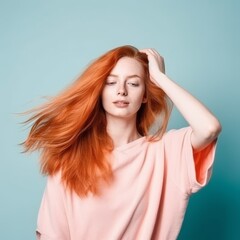 Fototapeta premium Woman with fiery red hair wearing a pink T-shirt on a blue background, casual beauty. Concept: personal confidence or hair styles