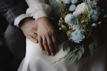 Wedding rings on the hands of the newlyweds, white gold rings on the hand of a man and a woman,...