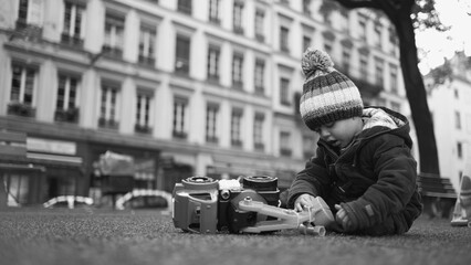 Small Boy at Play in Autumn Park Child Engrossed with Toy Truck in Chilly Weather captured in black...
