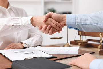 Lawyers shaking hands at table in office, closeup