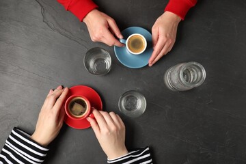 Women having coffee break at dark textured table, top view