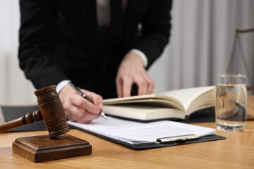 Lawyer working with documents at wooden table, focus on gavel