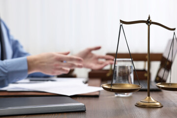 Lawyer working at wooden table, focus on scales of justice