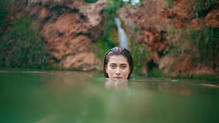 Fototapeta premium Attractive woman diving lagoon posing alone portrait. Seductive lady swimming