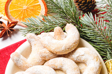 Obraz na płótnie Canvas Christmas horseshoe cookies, bagels with powdered sugar. Christmas tree branches for decoration. Light background