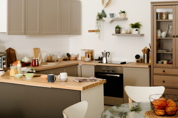 Part of modern spacious kitchen with row of cabinets hanging over counter with kitchenware and sink...