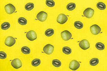 Green apple and kiwi on the yellow background. Pattern. Flat lay.