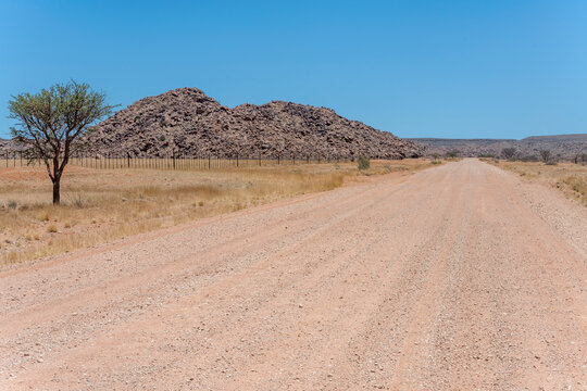 C27 gravel road and Dolerite boulders butte in Naukluft desert, west of Helmeringhausen,  Namibia