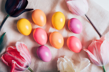 Colorful naturally dyed Easter eggs and beautiful fresh spring flowers in full bloom on table, top...