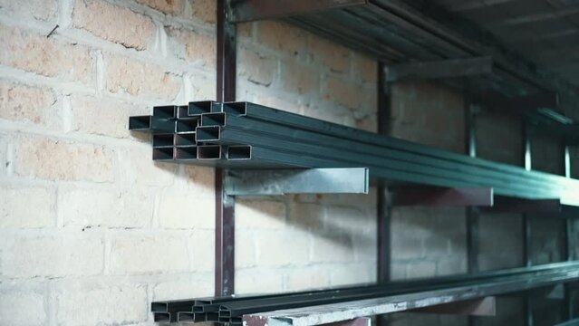 Steel shelves full of long metal profiles ready for further processing with hardware machines, metal frames used for construction purposes, stainless structure allows to create high quality metal